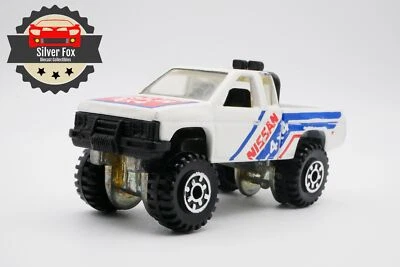 Nissan 1987 4x4 Harbody base metálica elevada blanca escala 1:64 diecast coleccionista Foto 1 de 4
