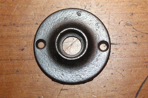 Round antique cast iron doorknob escutcheons with smooth metal finish and two screw holes on a wooden surface.