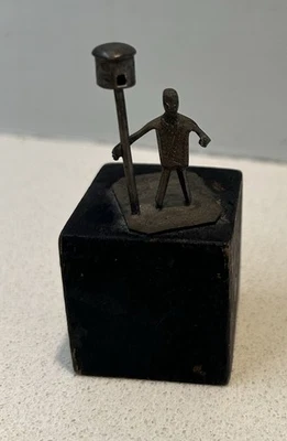 Pequeña escultura metálica del hombre sobre bloque de madera Foto 1 de 3