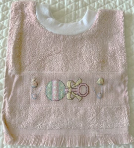 Babero de bebé pull-over cosido en cruz "Baby Rattle & Pins" rosa - NUEVO NUNCA USADO - Imagen 1 de 3
