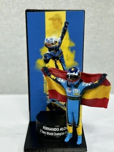 Figura 1/43 Fernando Alonso con bandera 2 Times World Champion F1 + Podium - Imagen 1 de 11
