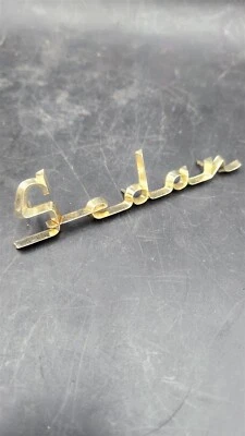 56 Cadillac Sedán deVille SEDAN Dorado Anodizado Guardabarros Escritura Emblema Insignia Foto 1 de 2