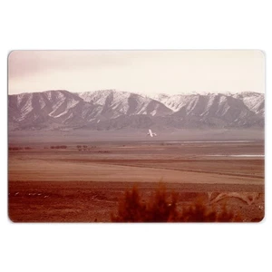 Foto eines kleinen Flugzeugs, das über Landschaft fliegt - 70er Jahre Berglandschaft - Bild 1 von 2