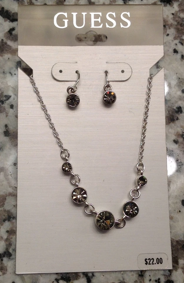 NUEVO CON ETIQUETAS, juego de pendientes + collar GUESS, tono plata, pedrería redonda color champán Foto 1 de 1
