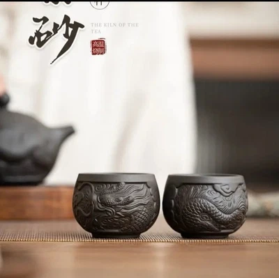 Un par de tazas de té de arcilla morada con patrones de dragón negro Foto 1 de 4