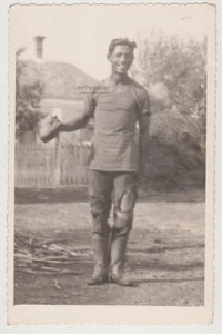 Lächelnder junger Mann in getragener Kleidung mit Mütze sonnenbeschienen Hof starke Freude Gay Int - Bild 1 von 7