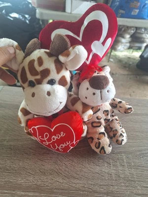 dos peluches, una jirafa y un animal estampado leopardo, ambos sosteniendo rojo... Foto 1 de 4
