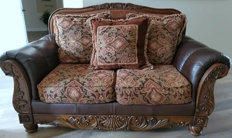 Pick up only FABRIC AND FAUX LEATHER LOVESEAT WITH ORNATE CARVED WOOD. Exc cond Cover