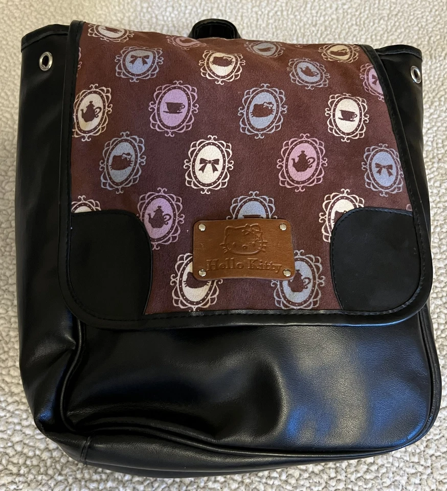 Mochila Sanrio Hello Kitty negra de imitación de cuero con solapa marrón estampada, 12 pulgadas Foto 1 de 4