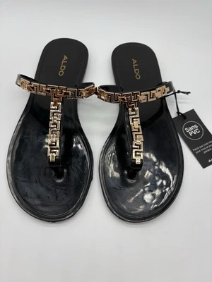 Sandalia de gelatina negra con correa en T Aldo Madila con patrón geométrico de metal dorado, 7 Foto 1 de 4