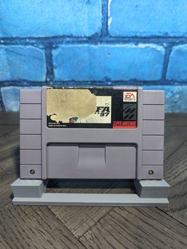 Gray Nintendo Super Famicom cartridge with black and white label reading “FIFA Soccer 97” and “EA Sports” in gold block letters.