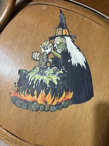 Halloween Hexe sitzt neben einem Feuer und rührt den Kessel - Bild 1 von 2