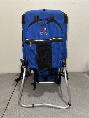 Mochila portabebés Kelty Kids azul de pie al aire libre senderismo Foto 1 de 4