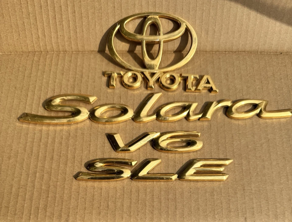 EMBLEMA MALETERO TOYOTA SOLARA SLE V6 2001-2004 OEM DORADO Foto 1 de 1