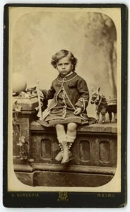 CDV 1880-90 A. Borderia à Reims. Garçon en robe avec ses jouets (Léon Varenne). - Foto 1 di 3