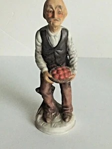 Estatuilla de cerámica vintage inclinada sobre abuelo 7 3/4"" sosteniendo frutas multicolor - Imagen 1 de 8