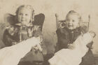 PORTRAIT OF ADORABLE SMILING GIRLS IN SMALL ROCKING CHAIRS W/ BABYDOLLS