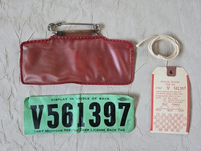Etiqueta trasera de licencia de ciervo residente de Michigan 1967 con soporte para etiqueta "The Red Buck" Foto 1 de 4