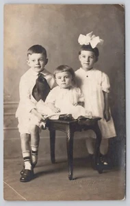 Postal RPPC Niño joven con corbata grande y niñas lazo en el pelo CYKO 1904-1920s - Imagen 1 de 2
