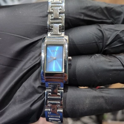 Delicado reloj DKNY para damas tono plateado esfera azul banda de 17 mm ajuste rectangular 7 funcionando Foto 1 de 4