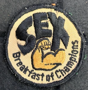 INSIGNIA PARCHE TELA ENVEJECIDA VINTAGE ORIGINAL 'SEXO - DESAYUNO DE CAMPEONES' - Imagen 1 de 3