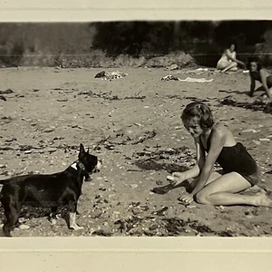 Fotografía instantánea vintage en blanco y negro niña ofreciendo adorable perro un refrigerio en la playa - Imagen 1 de 11