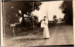 CARTOLINA RPPC donna che tiene bambino strada sporca persone cassetta postale scena di strada Ki11 - Foto 1 di 2