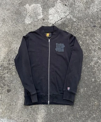 Chaqueta invicta para hombre grande negra con cremallera pista universitaria UNDFTD ropa de calle Foto 1 de 4