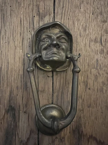 Antique or Vintage Door Knocker of Renaissance Person’s Face - Attached To Wood Cover