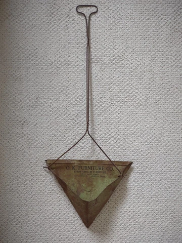 antique metal dust pan with long handle and store advertisement Cover