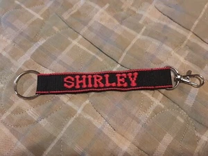 SHIRLEY bestickter Namensriemen Schlüsselanhänger, Schlüsselanhänger mit Verschluss (schwarz) - Bild 1 von 2