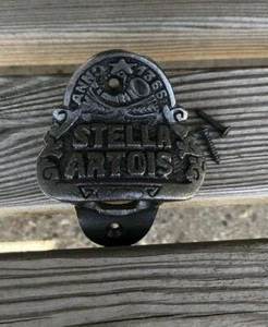 Barra de cerveza de hierro fundido "Stella Artois" abrebotellas montado en la pared / negro antiguo - Imagen 1 de 3