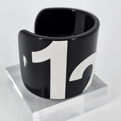 Brazalete de plástico gráfico blanco y negro Lacoste Bold Foto 1 de 4