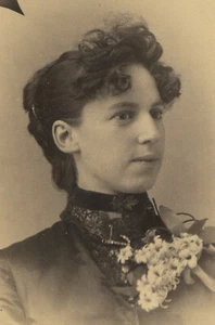 FRAU MIT LOCKIGEM PONY UND GROSSER GÄNSEBLÜMCHEN-CORSAGE. SCHRANKKARTE. NANAIMO, B.C. - Bild 1 von 1