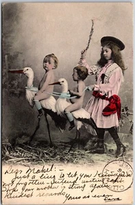 Postcard c1906 Babies Riding Storks Hand Tinted Artist Signed Maurice Andreossi - Bild 1 von 2