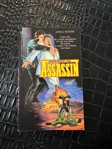 1983 JUSTIN PERRY THE ASSASSIN book by JOHN REVERE Paperback (UNREAD) - Imagen 1 de 1