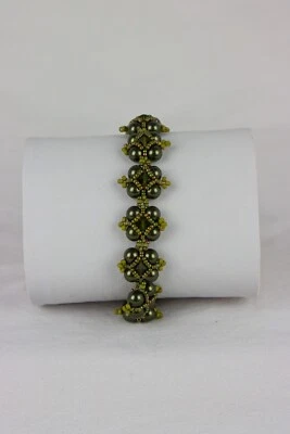 Pulsera de cuentas de vidrio verde oliva y semillas iridiscentes con tréboles centrales de cristal. Foto 1 de 4