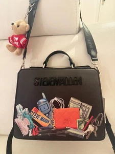 BOLSO BANDOLERA NUEVO CON ETIQUETAS STEVE MADDEN BEVELYN NEGRO CON ESTAMPADO DE CAOS CON ENCANTO DE OSO - Imagen 1 de 7