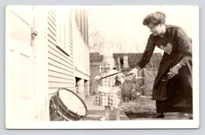 RPPC Frau mit Kleinkind spielt draußen mit einem Trommelstock um 1920 UNP Foto Postkarte - Bild 1 von 2