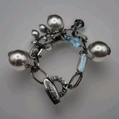 De colección. Pulsera Guess Pistola Gruesa Tono Metal con Dijes Plateados y Azul Claro Foto 1 de 4