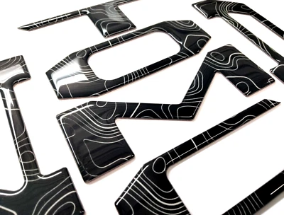 LETRAS TOPOGRÁFICAS 3D NEGRAS ABOVEDADAS PORTÓN TRASERO PARA TOYOTA TACOMA 2024-25 HECHAS EN EE. UU. Foto 1 de 2