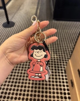 Chaveiro Coach x Peanuts 2025 Lucy bolsa de couro charme CBG58 rosa aniversário - Imagem 1 de 2