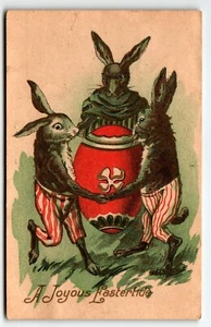 Alegre postal de Pascua conejos antropomórficos con pantalones bailando alrededor del huevo - Imagen 1 de 2