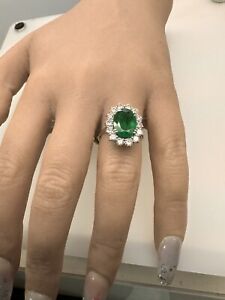 An emerald and diamond cluster ring .