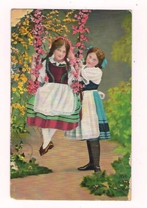 Postal de colección principios de 1900 2 niñas jugando en un columpio hecho de flores usadas - Imagen 1 de 2