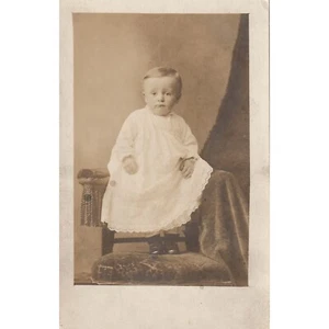 RPPC Foto Real Postal Niño Pequeño Vestido Largo De Parado En Silla Sin Publicar - Imagen 1 de 2