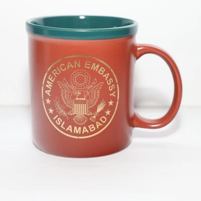 Taza de café AMEMB Islamabad Pakistán marrón verde cerámica escudo dorado Departamento de Estado de Estados Unidos Foto 1 de 4
