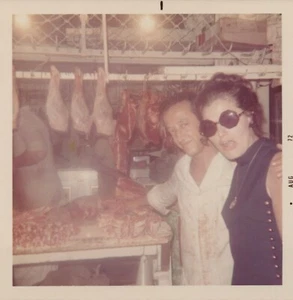 Vintage Foto - 70er Jahre - Mädchen steht mit blutigem Metzger mit hängendem Fleisch Griechenland - Bild 1 von 2