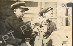 Altes antikes Foto von zwei gut gekleideten & hübschen Jungen, die ein Gewehr spannen 1910er - Bild 1 von 3