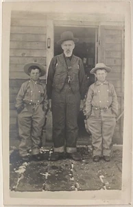 Postal con foto real RPPC ~ Dos niños con disfraces de vaquero idénticos de pie con papá - Imagen 1 de 3